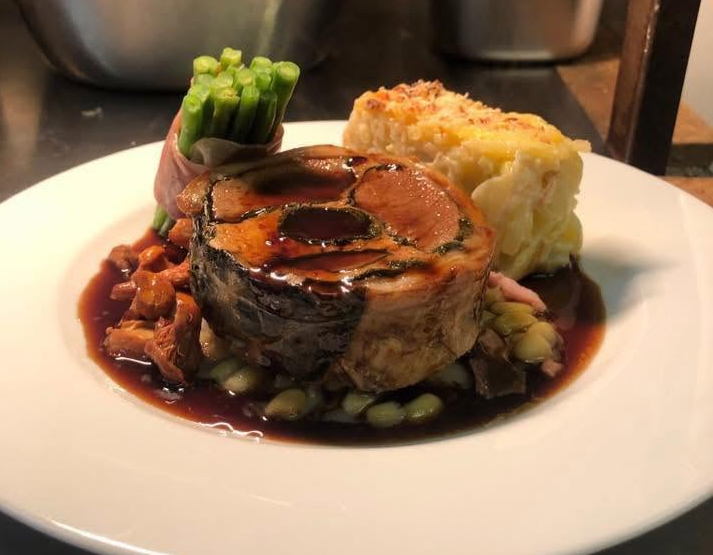 Slow roasted pork belly wrapped in Parma ham, with dauphinois potato, fine beans and red wine jus