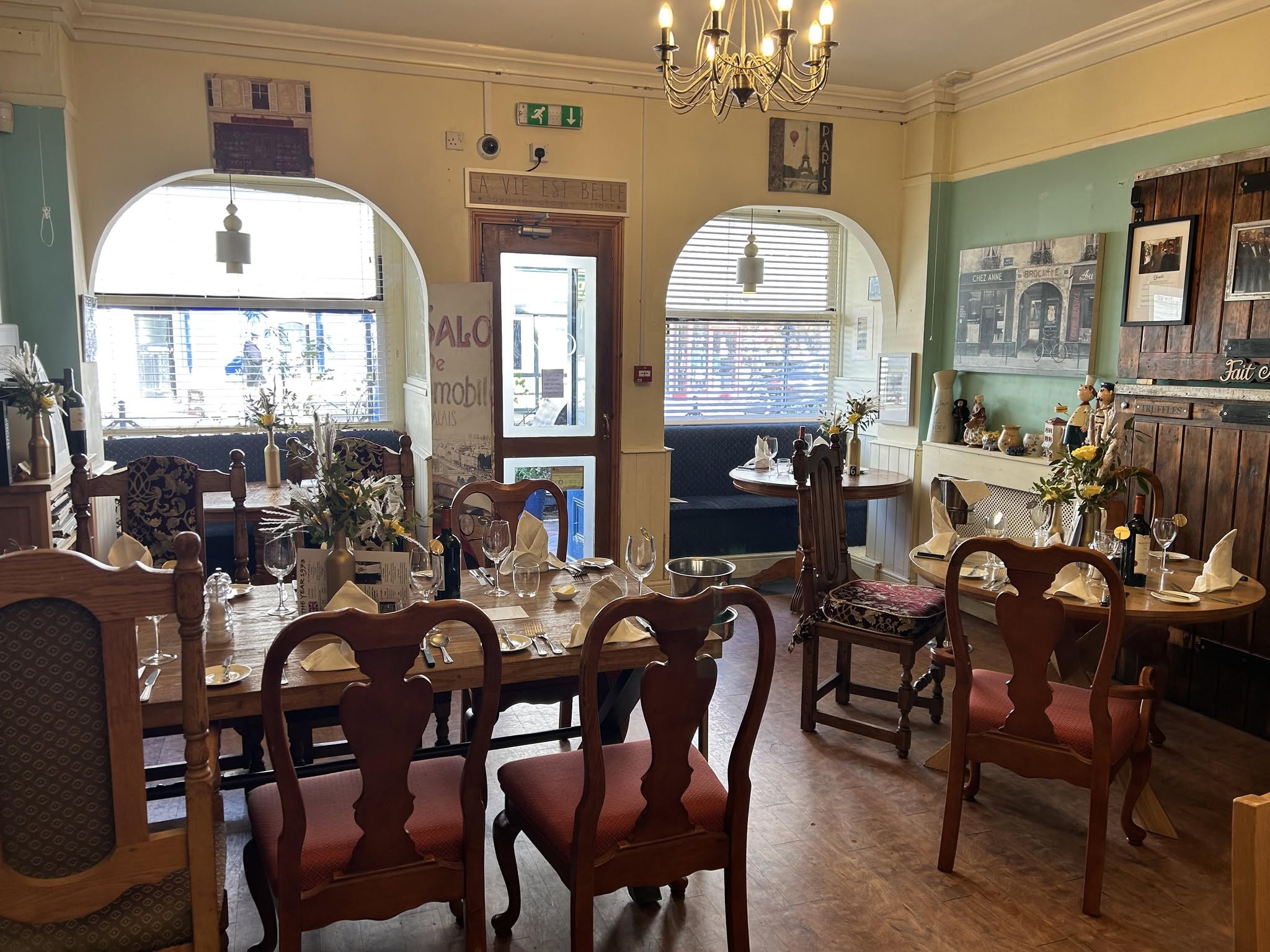 The Chez Moi dining room: laid tables, arched windows and a chandelier